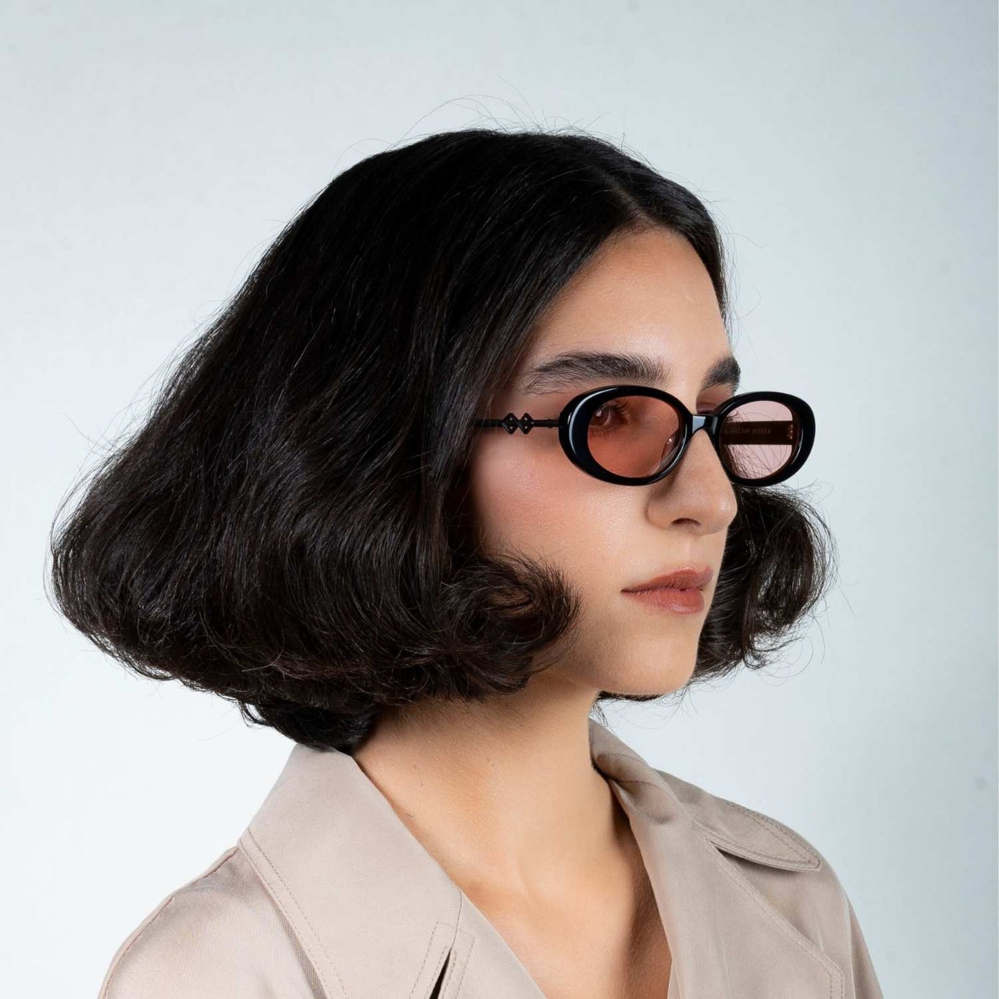 Side view of model wearing sunglasses | Oval sunglasses with pink lenses and black frames | Metal & Acetate | Olivia | Women's sunglasses | Karen Wazen Eyewear