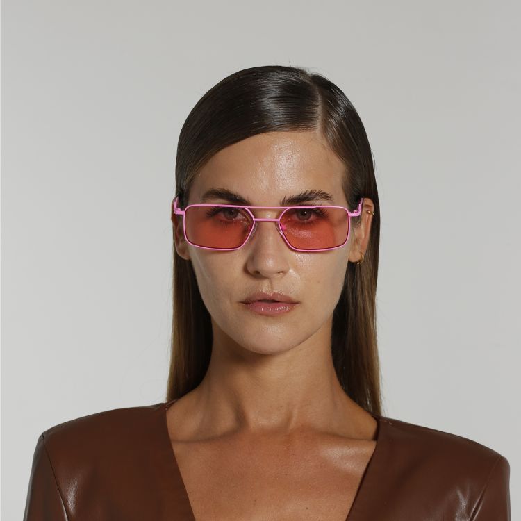 Front view of model wearing sunglasses | Rectangle sunglasses with pink lenses and pink frames | Metal | Devon | Women's, men's, and unisex sunglasses | Karen Wazen Eyewear