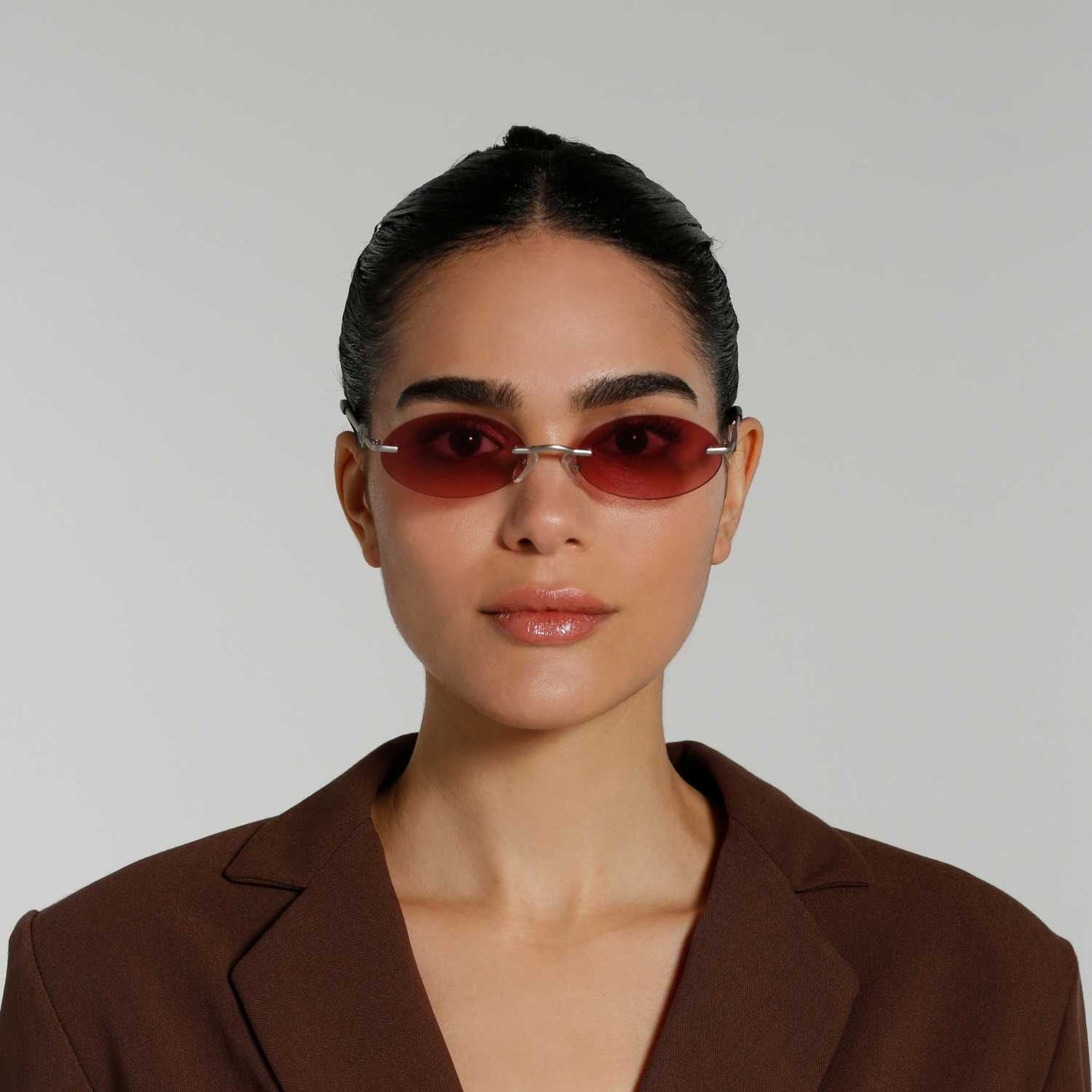 Front view of model wearing sunglasses | Oval sunglasses with red lenses and silver frames | Metal | Vicky | Women's sunglasses | Karen Wazen Eyewear